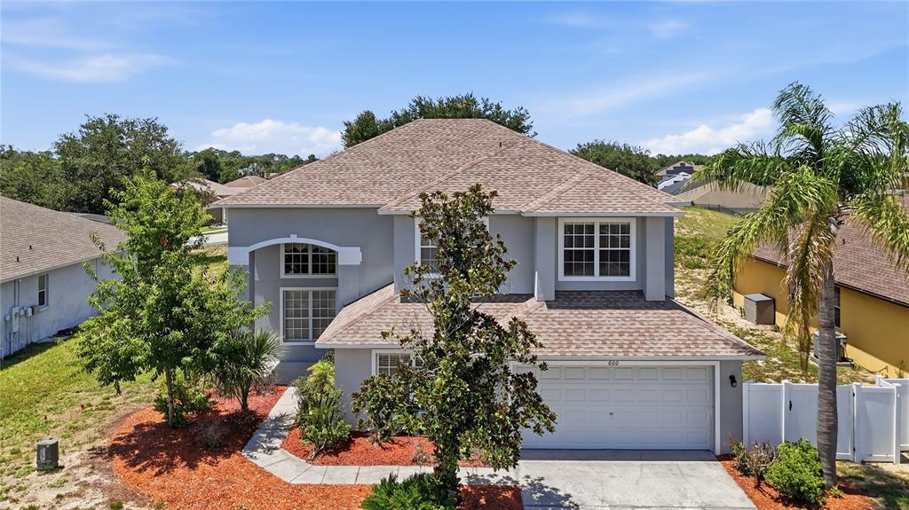 A two-story gray house with a shingled roof, a two-car garage, and a front yard — 600 WILDFLOWER ROAD, DAVENPORT, FL