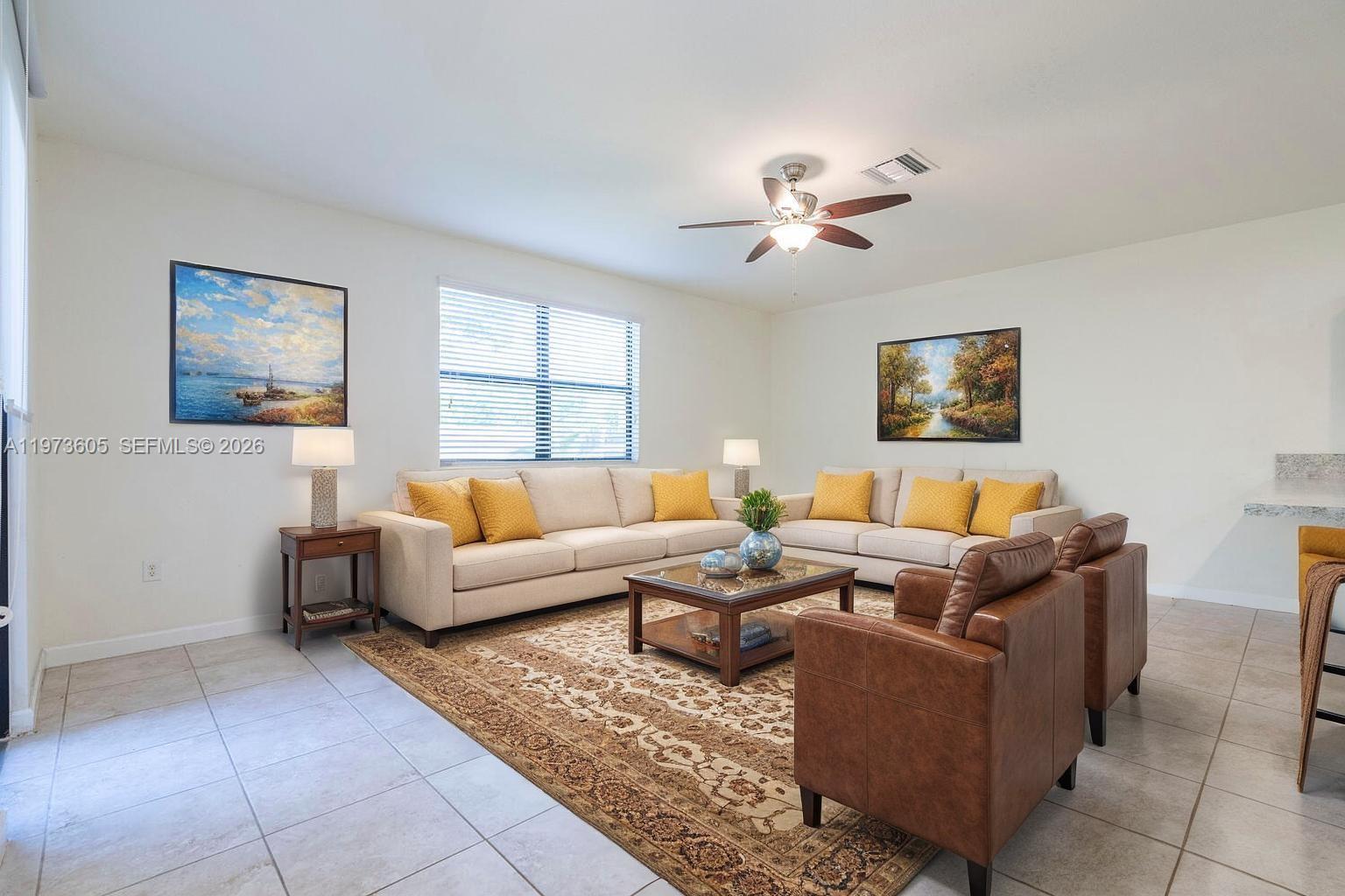 A living room features a beige sectional sofa, two leather armchairs, and a patterned rug — 516 SE 35th Ter, Homestead FL 33033, HOMESTEAD, FL