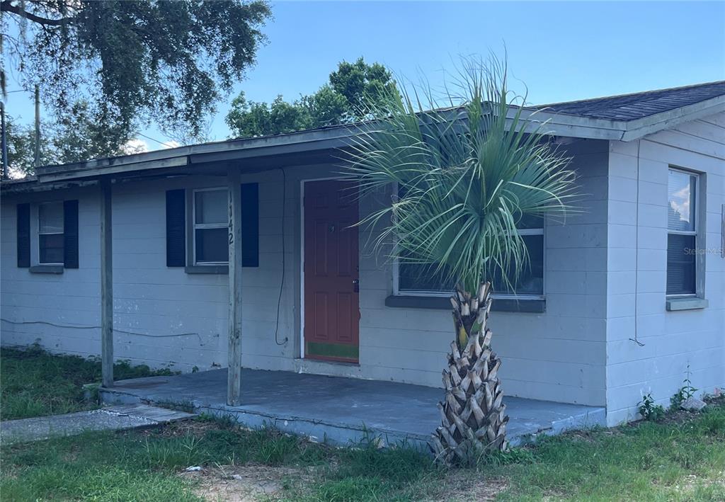 A single-story house with gray siding, a red front door, and a small front porch — 1142 MARTIN STREET, HAINES CITY, FL