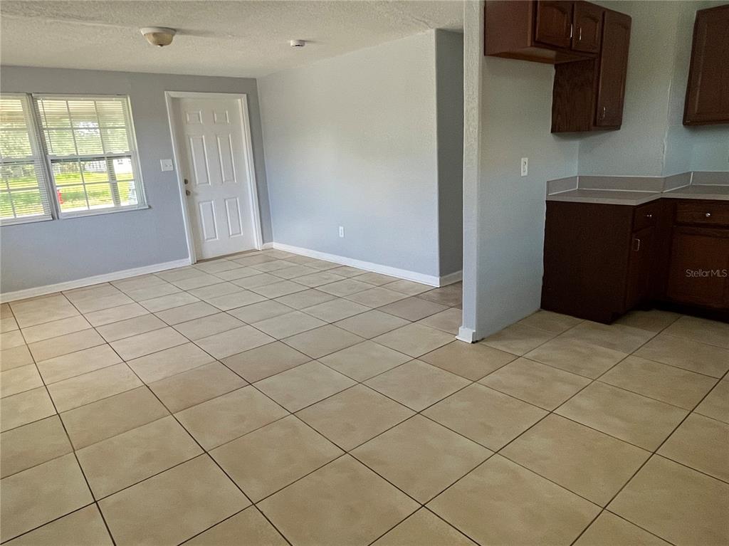 An open-concept room features light gray walls, beige floor tiles, and dark wood kitchen cabinets — 1142 MARTIN STREET, HAINES CITY, FL