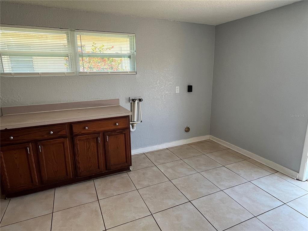 A laundry room features tile flooring, a wooden cabinet with a countertop, and wall-mounted hookups — 1142 MARTIN STREET, HAINES CITY, FL
