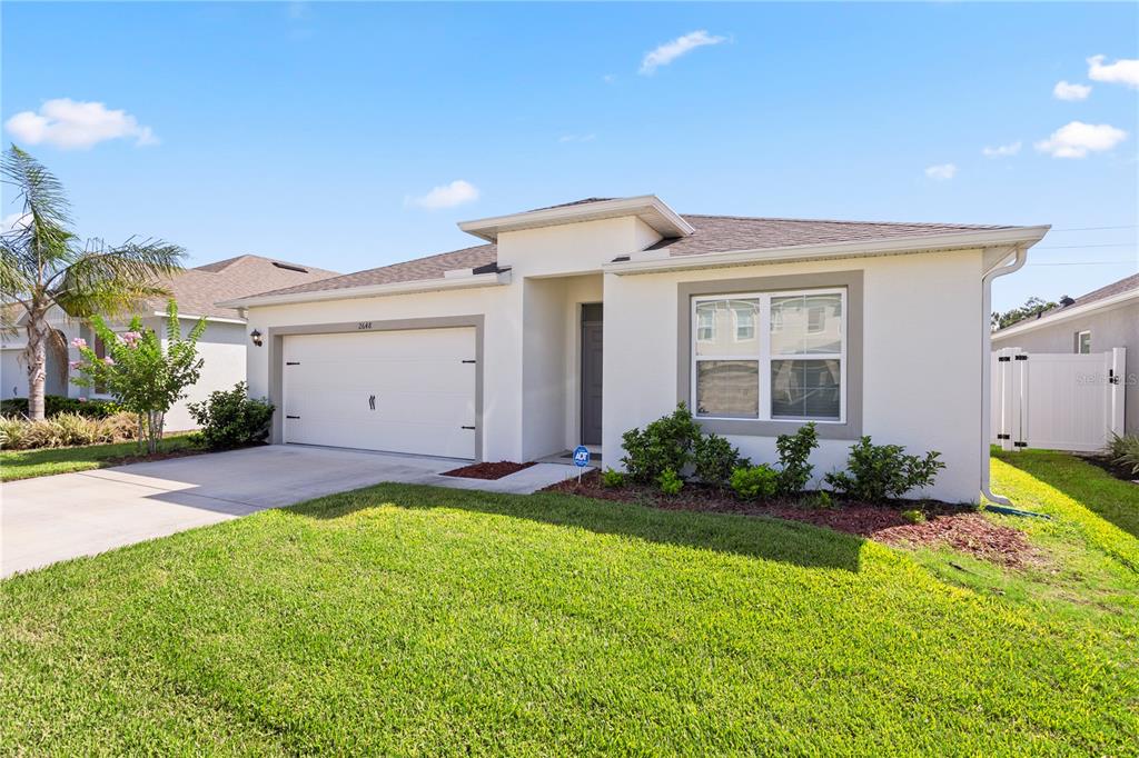 A single-story house with a white stucco exterior, a two-car garage, and a front lawn — 2648 NEVERLAND DRIVE, NEW SMYRNA BEACH, FL