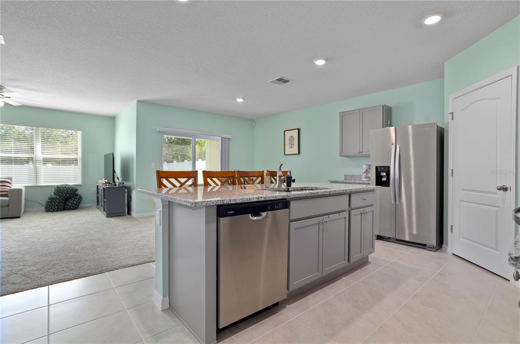 A kitchen with a granite-topped island, stainless steel dishwasher, and gray cabinets — 2648 NEVERLAND DRIVE, NEW SMYRNA BEACH, FL