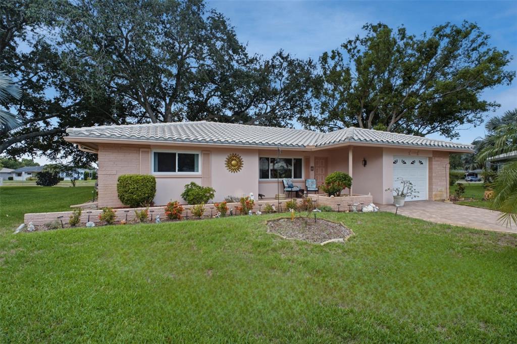 A single-story pink house with a tiled roof, a front porch, and a paved driveway — 1520 KENMORE COURT, PALM HARBOR, FL