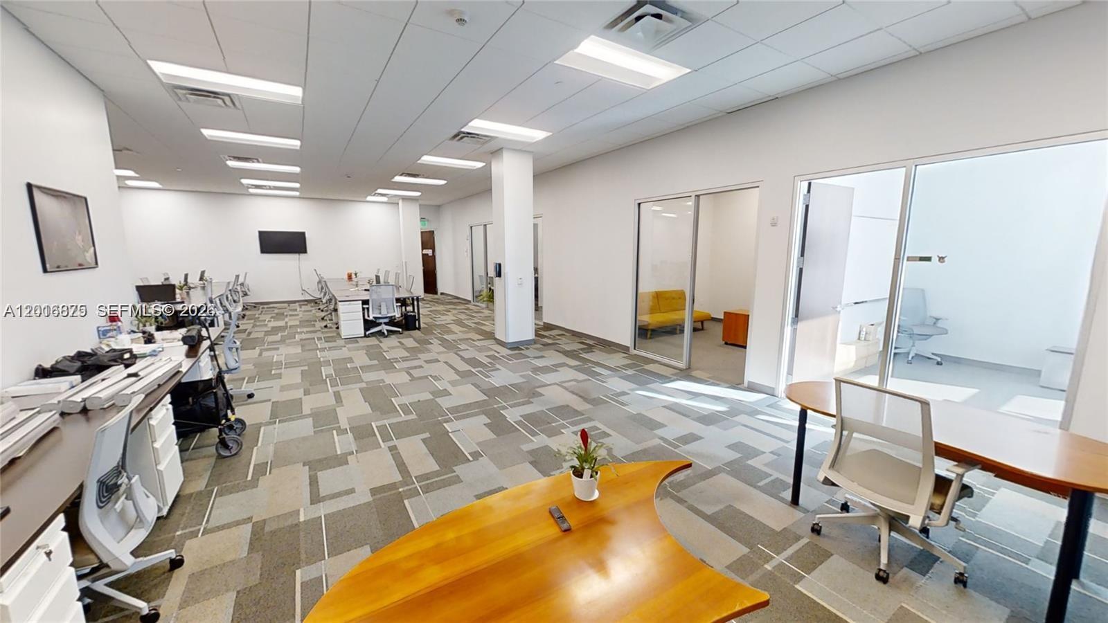 An open-plan office space features modular desks, carpeted flooring, and glass-enclosed private rooms — 1501 Biscayne # 501, Miami FL 33132, MIAMI, FL