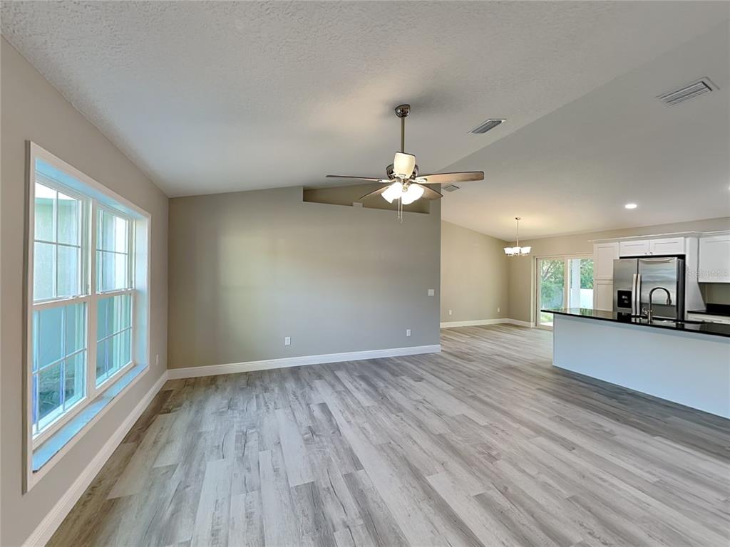 An open-concept living area features light gray wood-look flooring, a ceiling fan, and a kitchen — 2082 W SWANSON DRIVE, CITRUS SPRINGS, FL