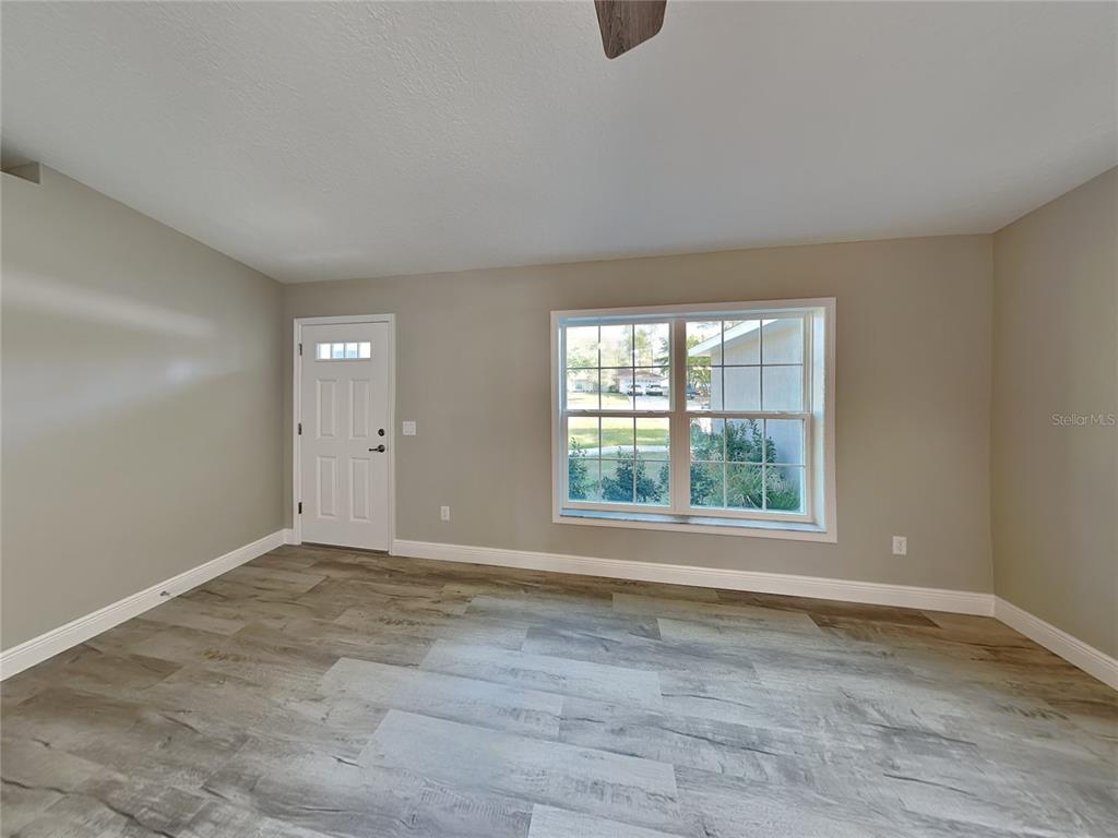 An empty room features light gray walls, wood-look flooring, a white door, and a window — 2082 W SWANSON DRIVE, CITRUS SPRINGS, FL
