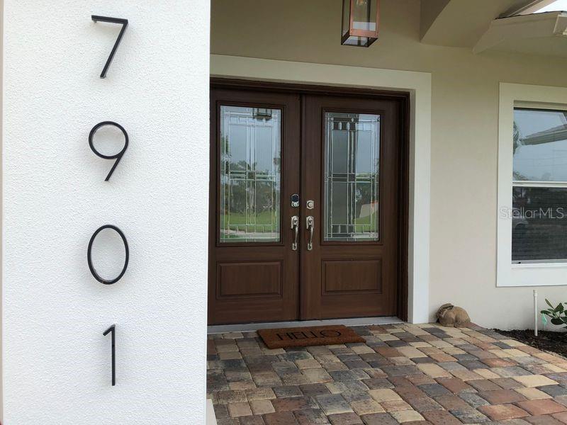 The exterior entrance features a paved walkway, double wooden doors, and a covered porch area — 7901 10TH AVENUE S, ST PETERSBURG, FL