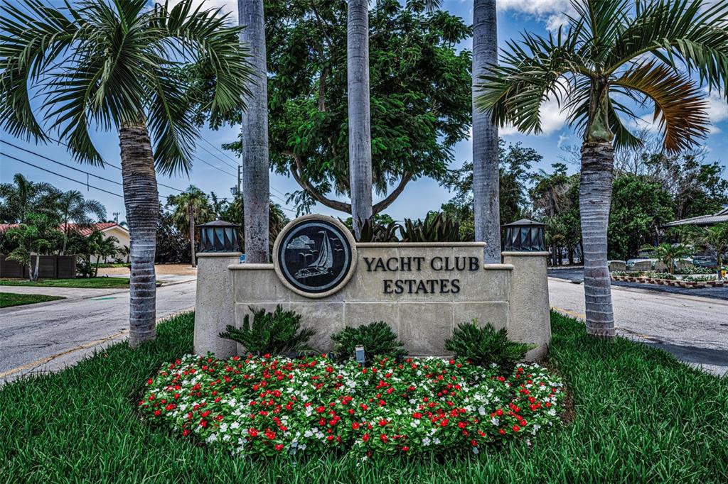 A stone monument sign for Yacht Club Estates stands surrounded by palm trees and flowers — 7901 10TH AVENUE S, ST PETERSBURG, FL