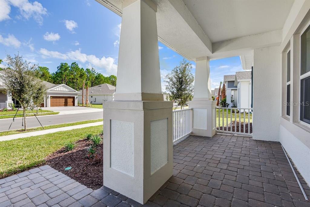 A blue front door with sidelights sits on a brick porch next to a wooden bench — 668 JUNONIA BOULEVARD, NEW SMYRNA BEACH, FL
