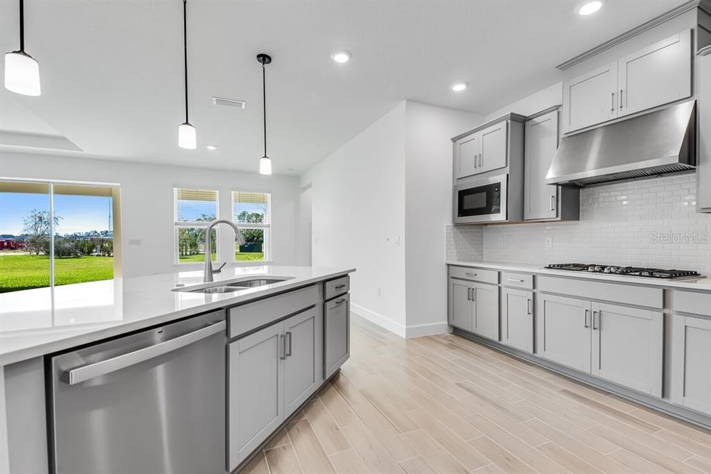 An open-concept living and dining area features light wood-look tile floors and sliding glass doors — 668 JUNONIA BOULEVARD, NEW SMYRNA BEACH, FL