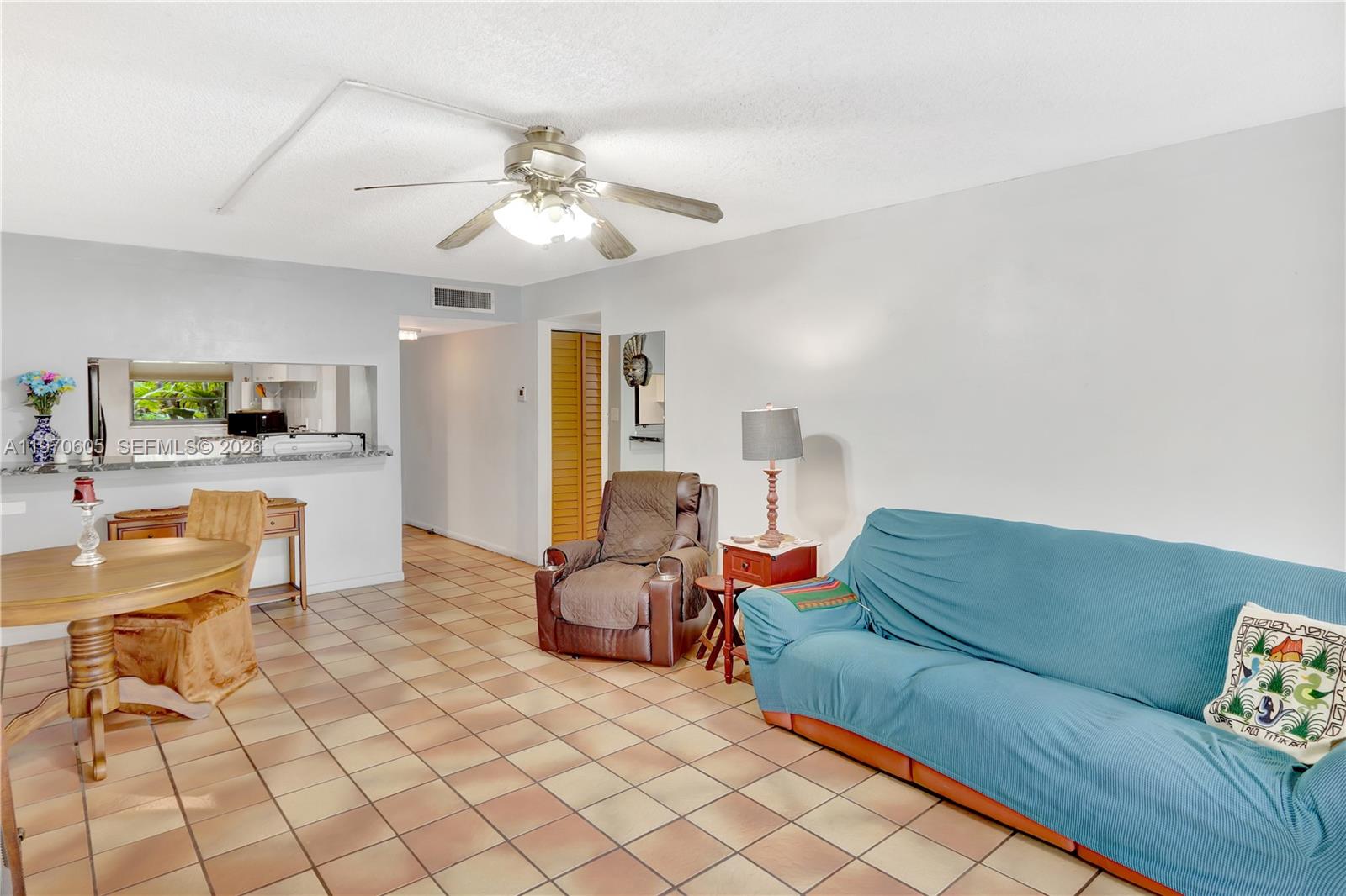 A living room features a blue sofa, brown recliner, dining table, and tiled flooring — 10525 SW 112th Ave # 117, Miami FL 33176, MIAMI, FL