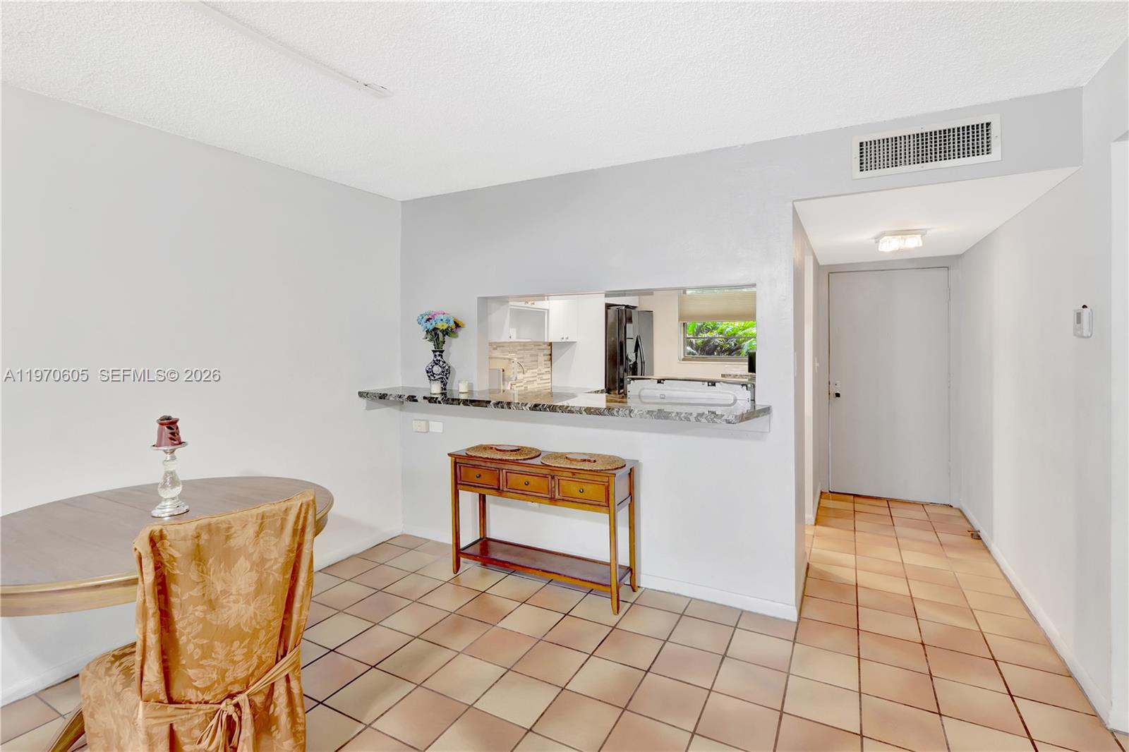 A dining area features tile flooring, a pass-through window to the kitchen, and a console table — 10525 SW 112th Ave # 117, Miami FL 33176, MIAMI, FL