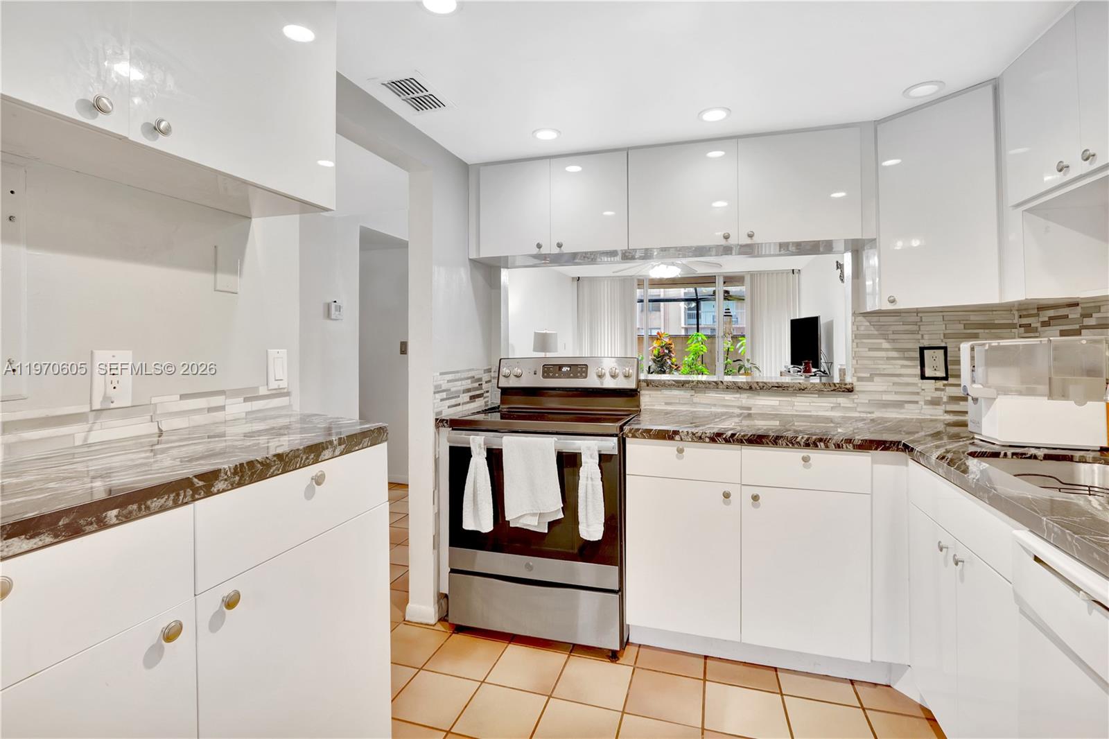 A kitchen with white cabinets, dark marble countertops, stainless steel appliances, and tiled flooring — 10525 SW 112th Ave # 117, Miami FL 33176, MIAMI, FL