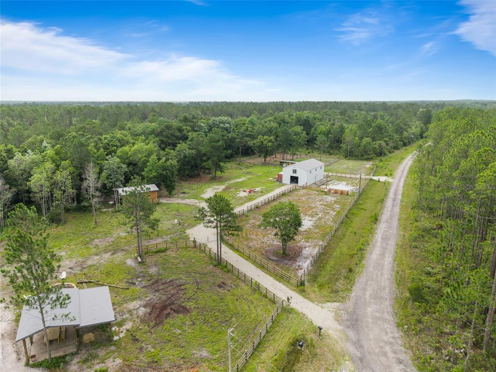 An aerial view of a rural property featuring a white barn, outbuildings, and fenced pastures — TBD RETREAT ROAD, KEYSTONE HEIGHTS, FL