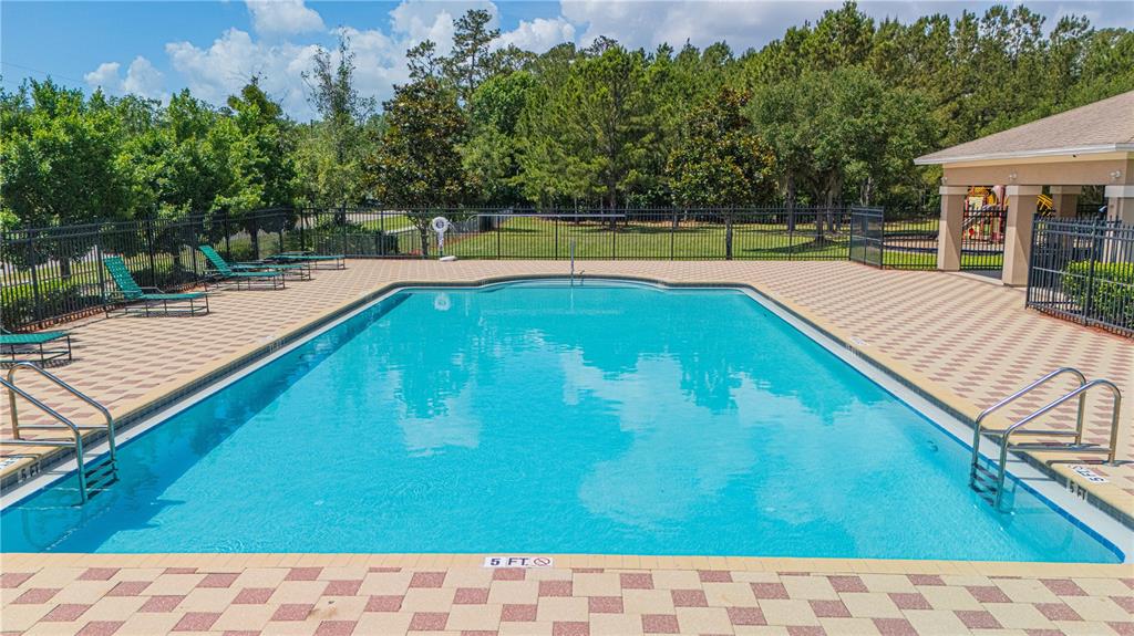 A rectangular swimming pool with a tiled deck is surrounded by a black metal fence — 12101 ALEXANDRA DRIVE, JACKSONVILLE, FL
