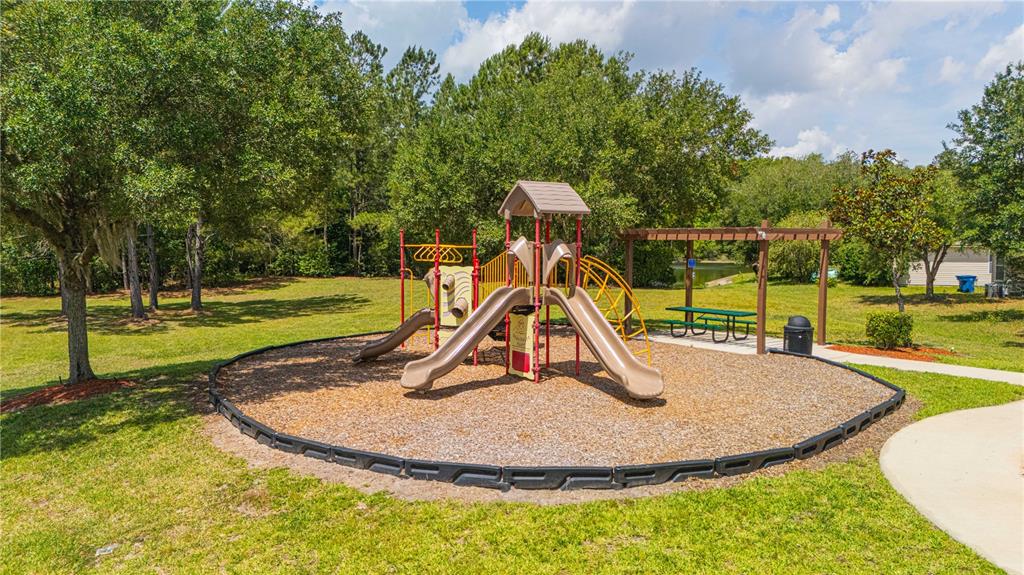 A playground with slides and a picnic table sits on a wood-chipped area outdoors — 12101 ALEXANDRA DRIVE, JACKSONVILLE, FL
