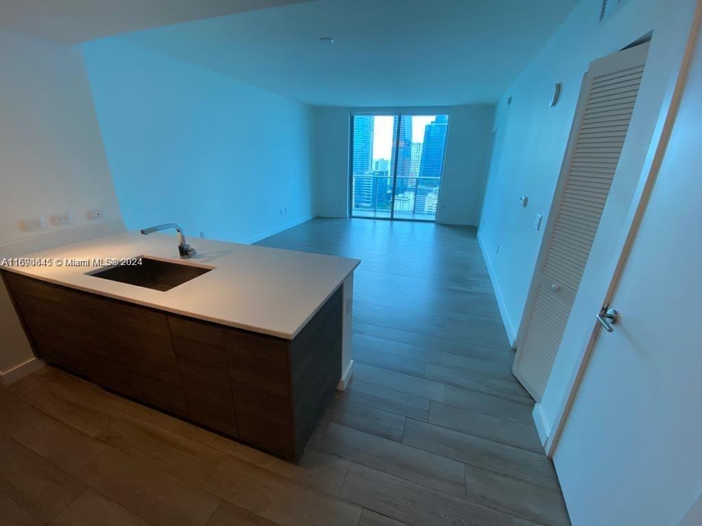 An open-concept kitchen with a dark island and white countertop overlooks a living area — 1100 S Miami Ave # 2602, Miami FL 33130, MIAMI, FL