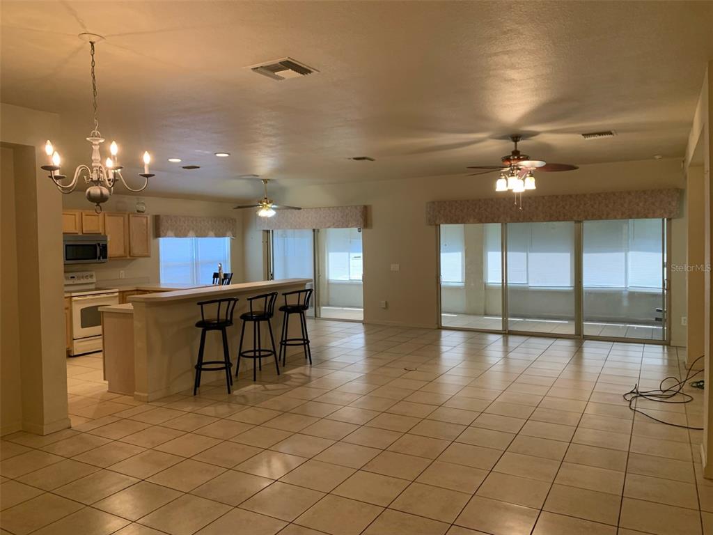 An open-concept kitchen and living area features tile flooring, a breakfast bar, and sliding doors — 4311 SW 53RD TERRACE, OCALA, FL