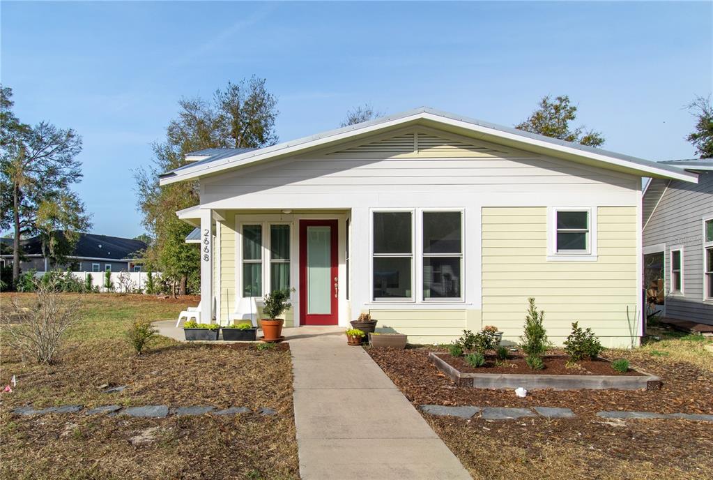 A single-story house with light yellow siding, a red front door, and a concrete walkway — 2668 NW 47TH TERRACE, GAINESVILLE, FL