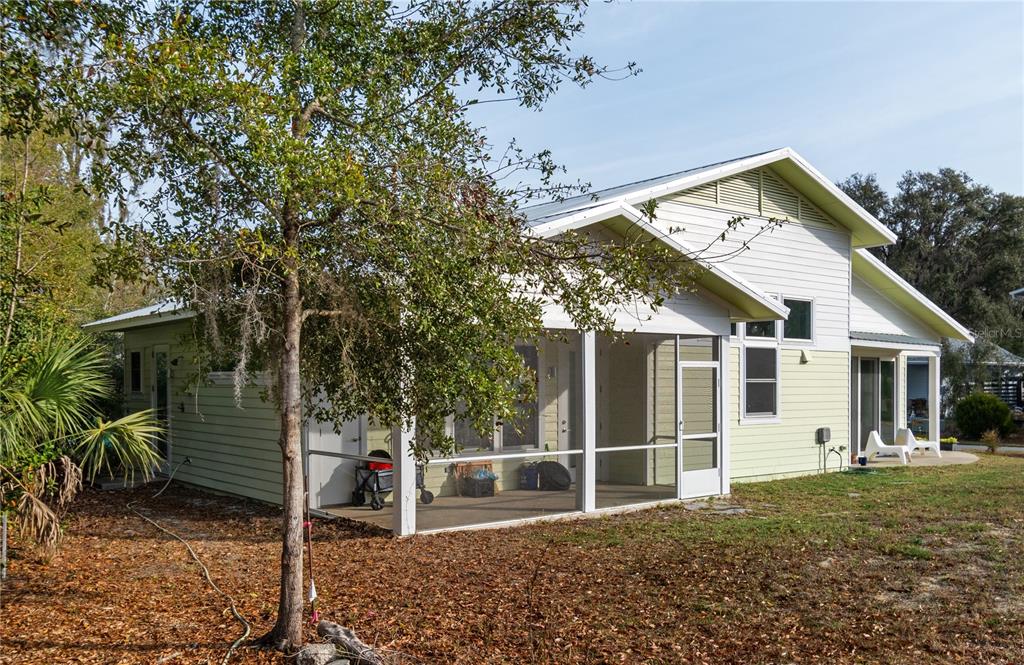 The exterior of a light green house features a screened-in porch and a metal roof — 2668 NW 47TH TERRACE, GAINESVILLE, FL