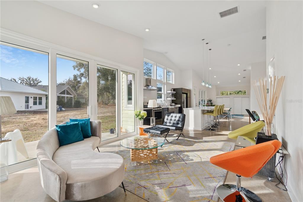 A bright, open-concept living room and kitchen area with large sliding glass doors and furniture — 2668 NW 47TH TERRACE, GAINESVILLE, FL