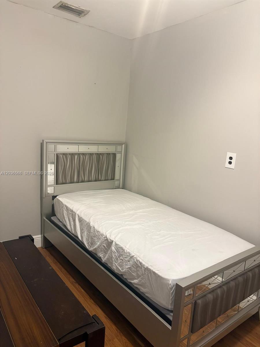 A bedroom features a silver-framed twin bed with a white mattress against a plain wall — 610 NE 4th Pl # 1, Hialeah FL 33010, HIALEAH, FL
