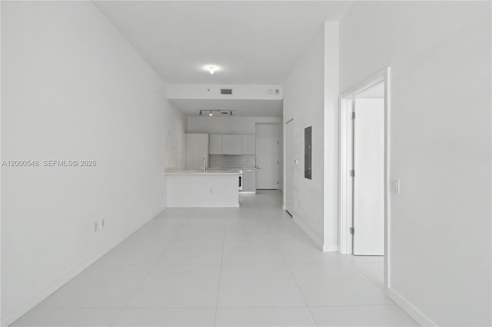 A modern, open-concept living and dining area features white tile floors and a kitchen island — 501 NE 31st St # 302, Miami FL 33137, MIAMI, FL