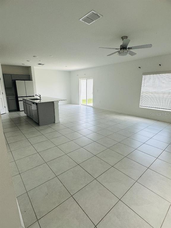 An open-concept kitchen and living area features light tile flooring and a center island — 2847 BIG SUR ROAD, DAVENPORT, FL
