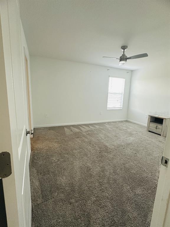 A carpeted bedroom features a ceiling fan, a window with blinds, and a small cabinet — 2847 BIG SUR ROAD, DAVENPORT, FL
