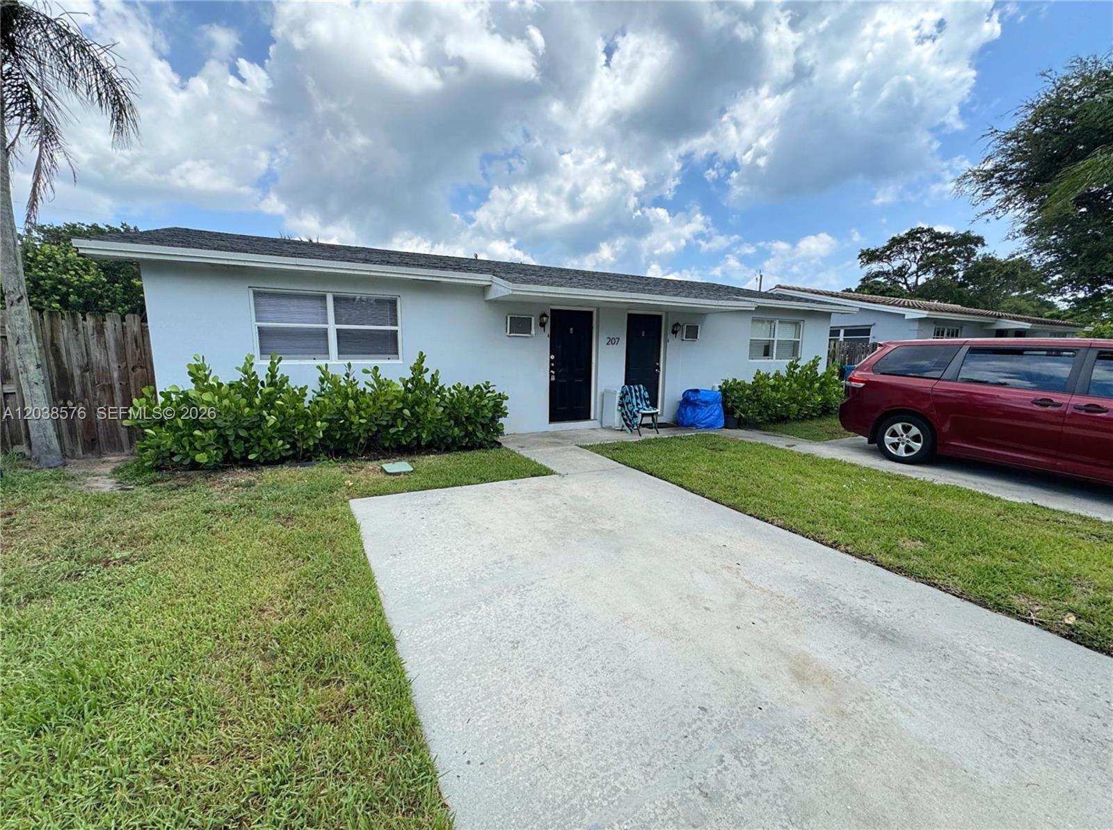A single-story duplex with a concrete driveway, two black front doors, and green landscaping — 207 SE 4th Ave, Boynton Beach FL 33435, BOYNTON BEACH, FL
