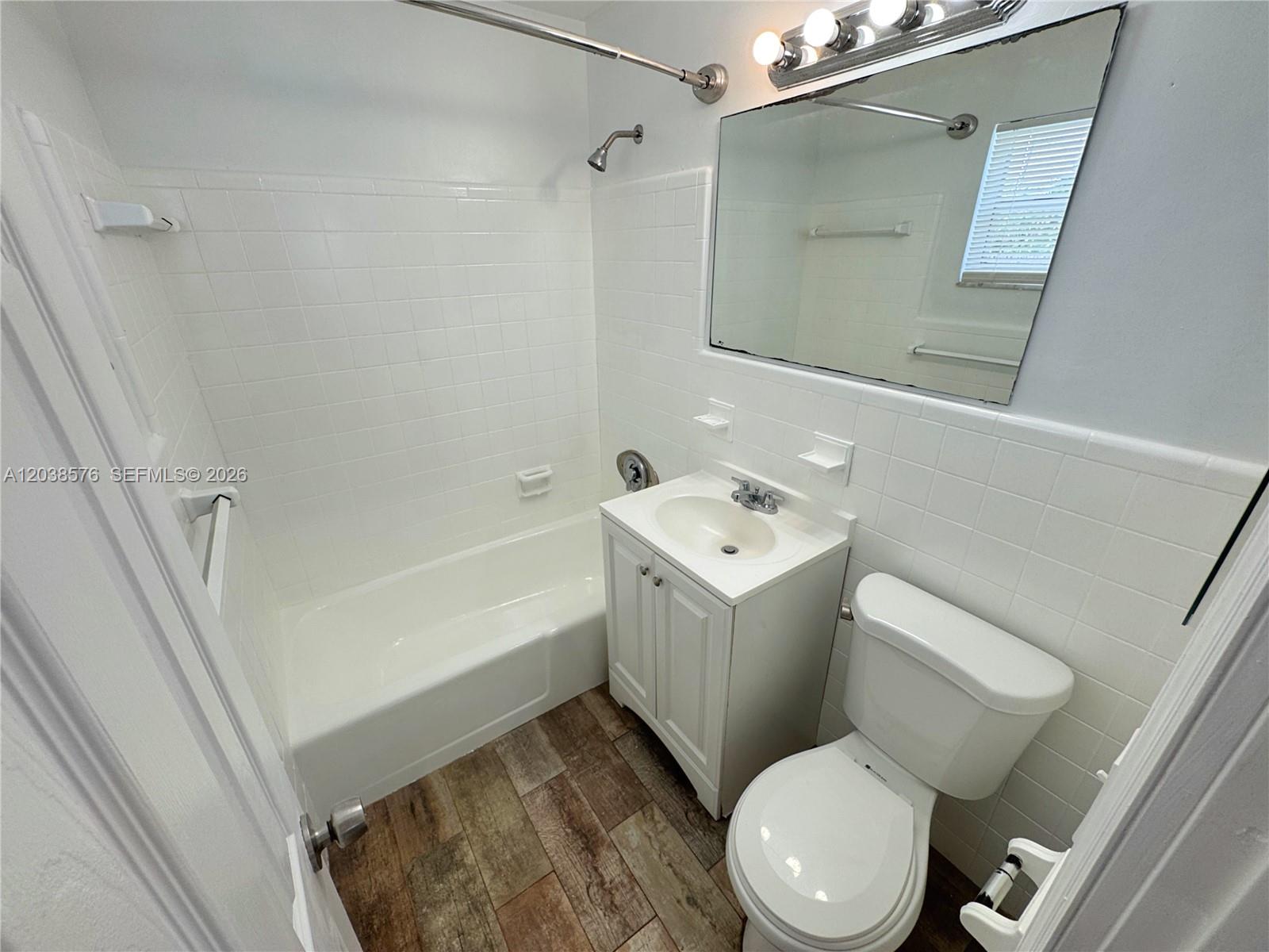 A bathroom features a white vanity, a toilet, and a tiled shower-tub combination — 207 SE 4th Ave, Boynton Beach FL 33435, BOYNTON BEACH, FL