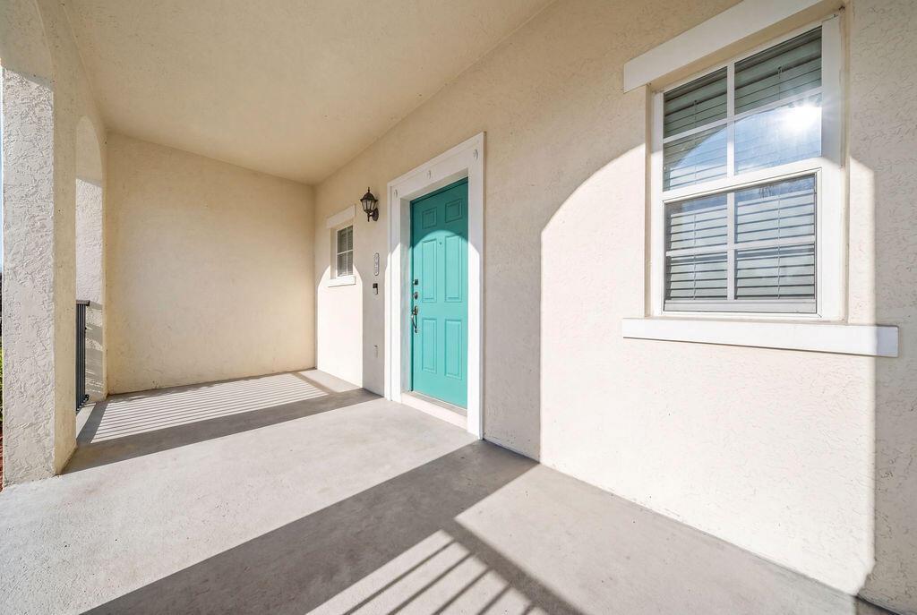 A covered concrete porch features a teal front door and a single window — 261 SW 6th Place, Pompano Beach FL 33060, POMPANO BEACH, FL