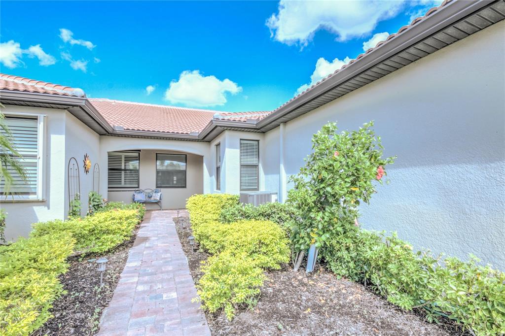 A brick walkway leads to the recessed entryway of a house with a tile roof — 18837 LANUVIO STREET, VENICE, FL