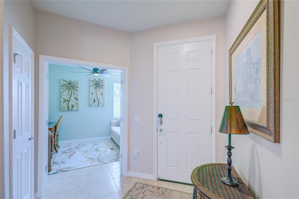 An entryway features a white door, a tiled floor, a wicker table, and a doorway — 18837 LANUVIO STREET, VENICE, FL