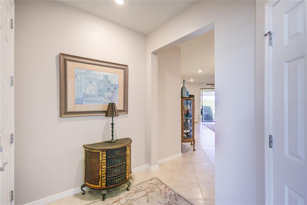 A foyer features a small chest with a lamp, a framed print, and tiled flooring — 18837 LANUVIO STREET, VENICE, FL