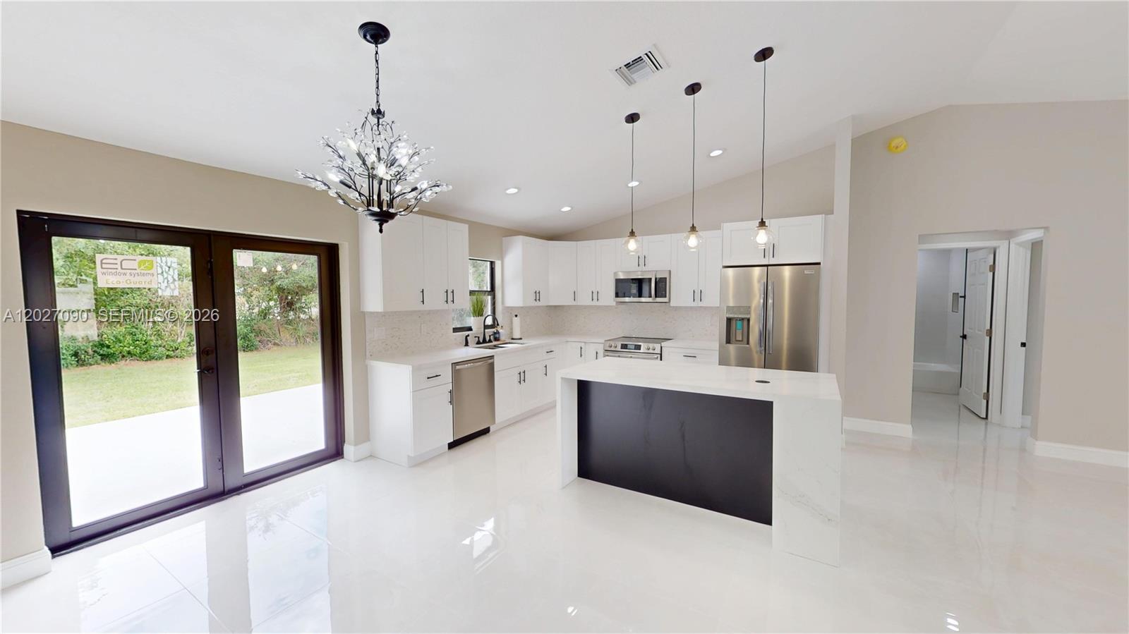 A modern kitchen features white cabinetry, quartz countertops, a black island, and stainless steel appliances — 4726 Trout Ave, Sebring FL 33870, SEBRING, FL