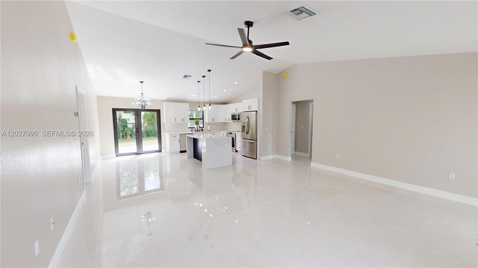 A modern open-concept kitchen features white cabinetry, a central island, and polished tile flooring — 4726 Trout Ave, Sebring FL 33870, SEBRING, FL