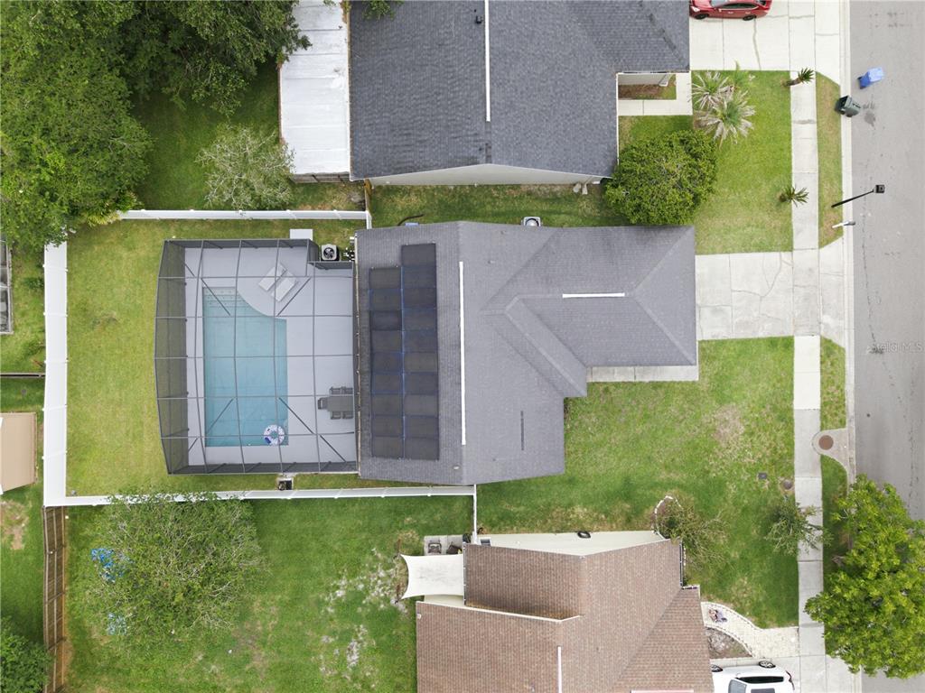 An aerial view shows a house with a screened-in pool and solar panels on the roof — 1119 COVINGTON STREET, OVIEDO, FL