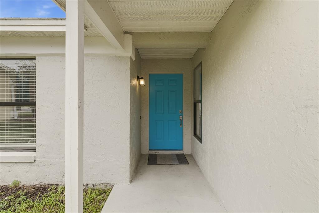 A covered entryway features a bright blue front door and a concrete porch floor — 1119 COVINGTON STREET, OVIEDO, FL