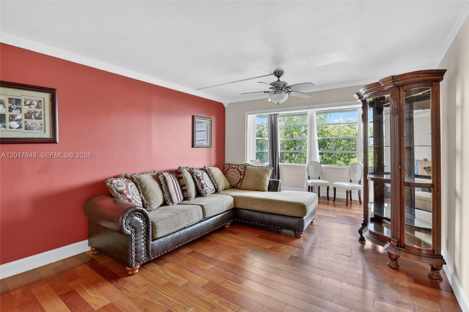 A living room features a red accent wall, a sectional sofa, and hardwood flooring — 6600 Cypress Rd # 504, Plantation FL 33317, PLANTATION, FL