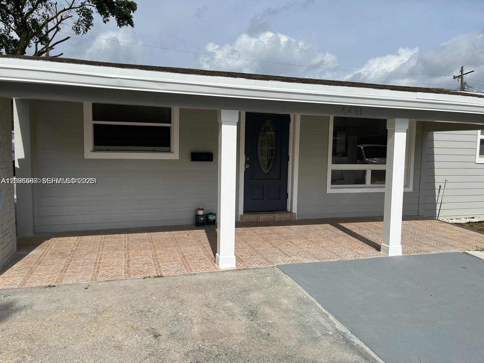A single-story house exterior features gray siding, a covered porch with tiled flooring, and white columns — 6431 Hayes St, Hollywood FL 33024, HOLLYWOOD, FL