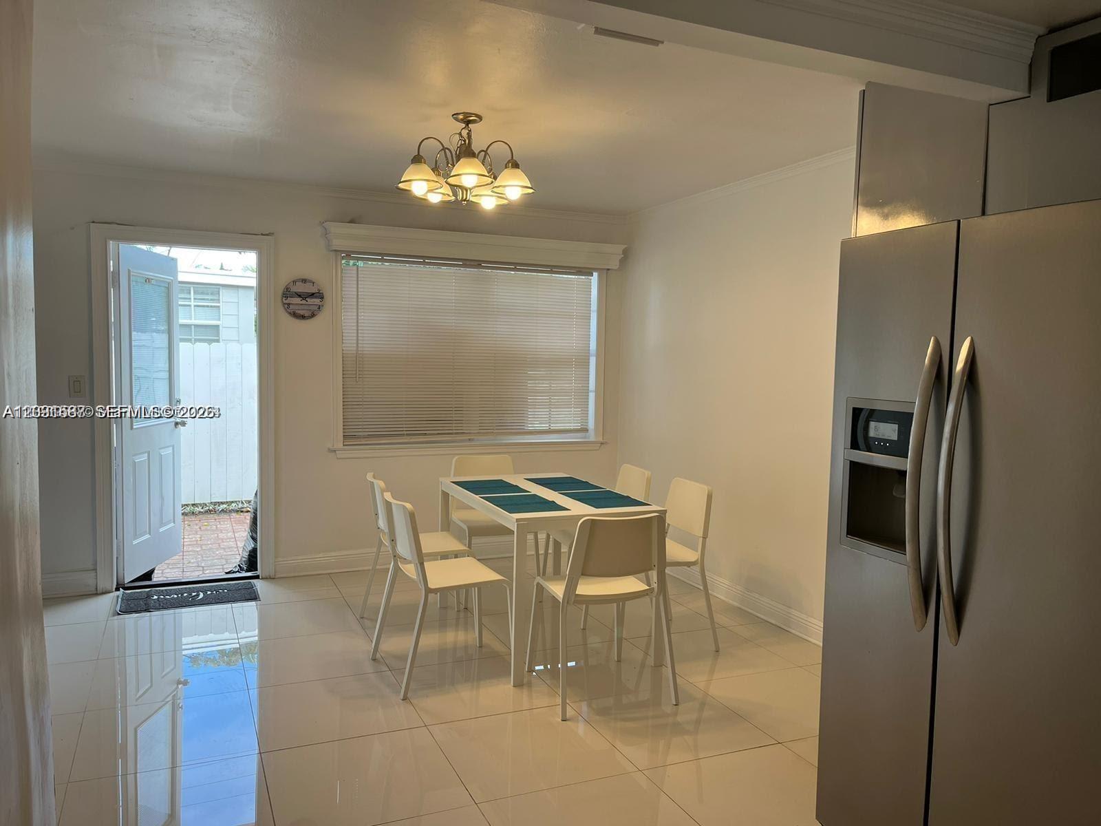 A dining area features a white table with four chairs, tile flooring, and a chandelier — 6431 Hayes St, Hollywood FL 33024, HOLLYWOOD, FL