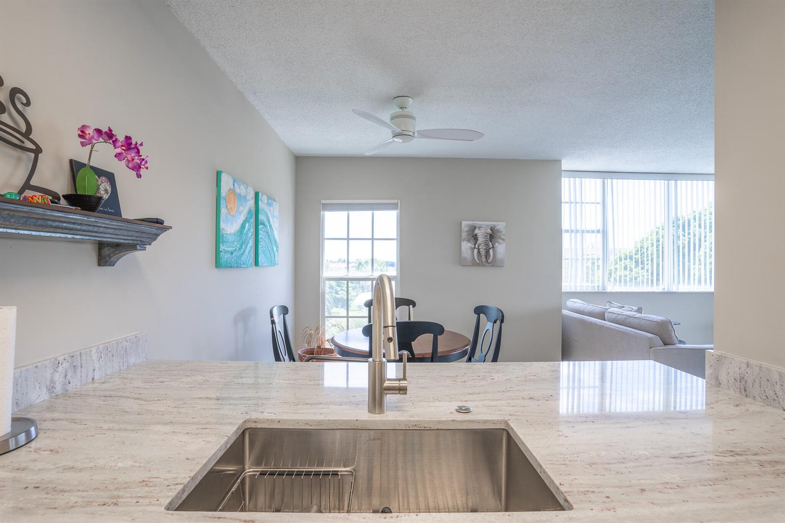 A kitchen sink with a stainless steel faucet overlooks a dining area and living room — 250 NE 20th Street # 4190, Boca Raton FL 33431, BOCA RATON, FL