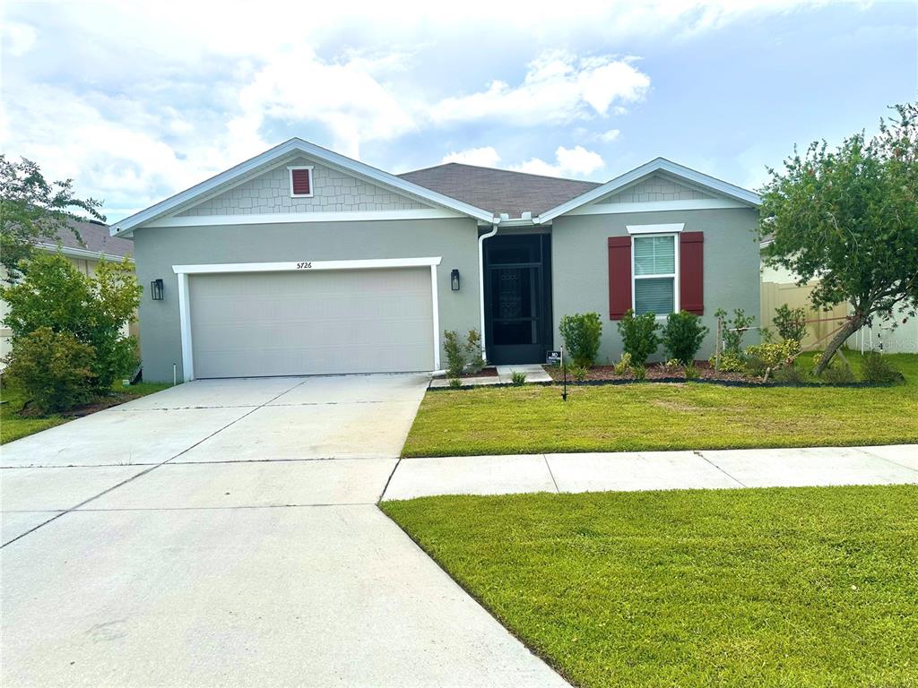 A single-story house with a two-car garage, gray stucco siding, and a screened entryway — 5726 ARLINGTON RIVER DRIVE, LAKELAND, FL