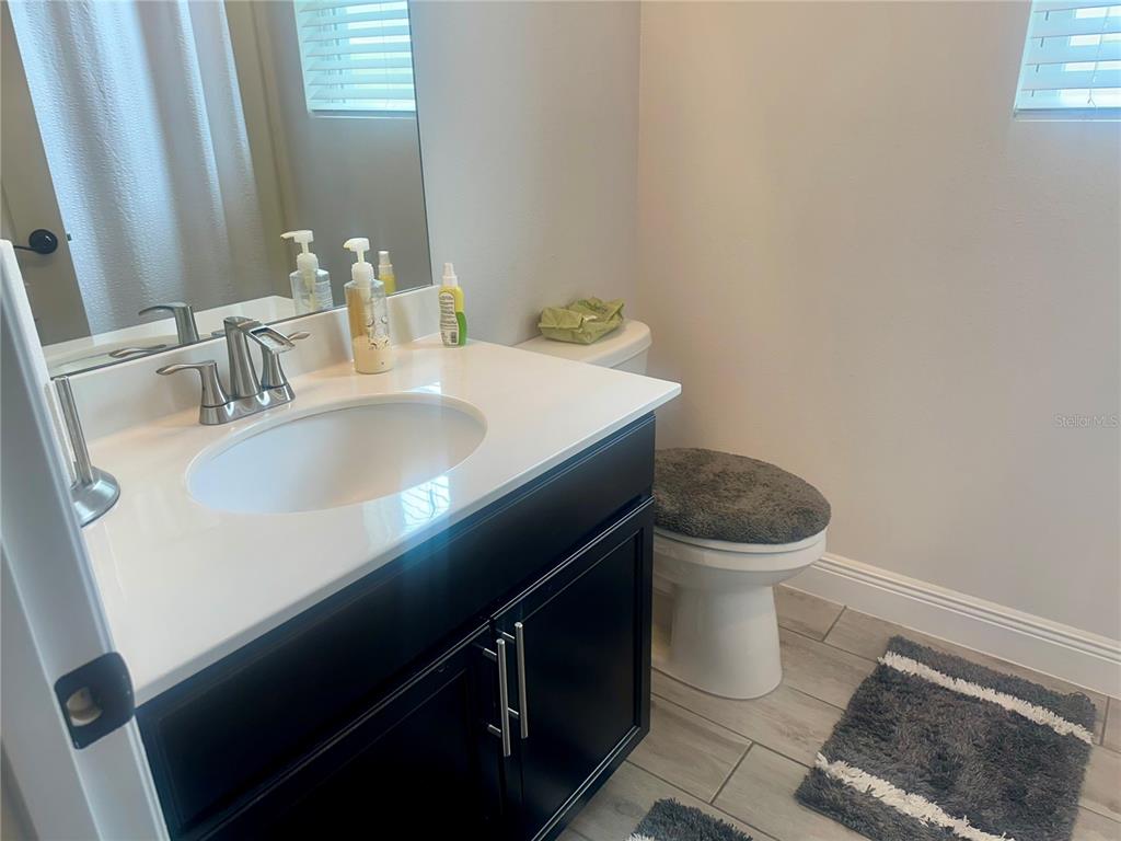 A bathroom features a dark vanity with a white countertop, a mirror, and a toilet — 5726 ARLINGTON RIVER DRIVE, LAKELAND, FL