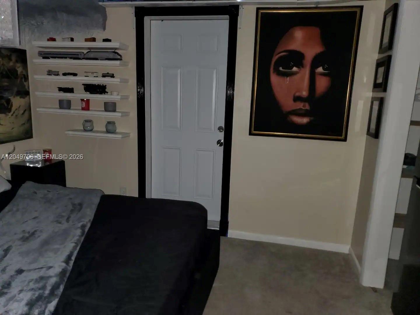 A bedroom features a white door, wall-mounted display shelves, and a large portrait painting — 804 NW 8th St, Dania Beach FL 33004, DANIA BEACH, FL