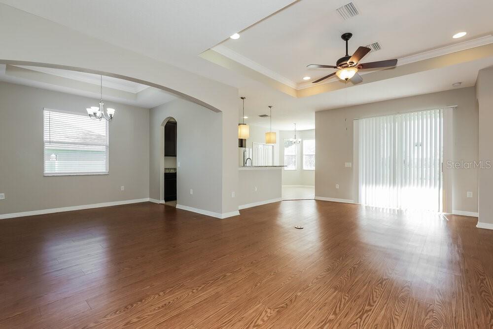 An open-concept living and dining area features light gray walls, wood flooring, and recessed lighting — 3911 CONSTANTINE LOOP, WESLEY CHAPEL, FL