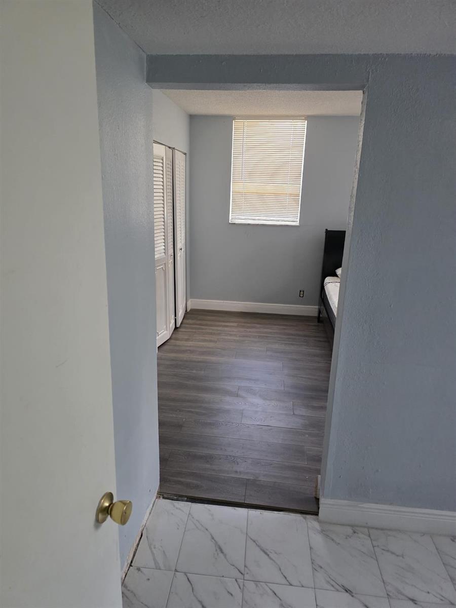 A view through a doorway into a bedroom with wood-look flooring and white closets — 3130 Holiday Springs Boulevard # 104, Margate FL 33063, MARGATE, FL