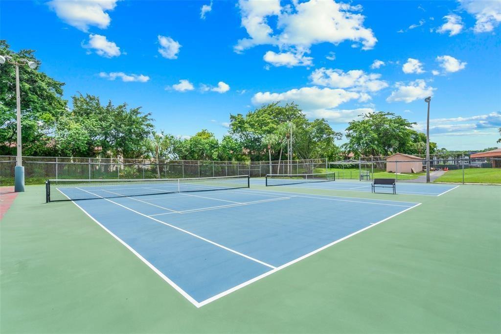 A blue and green outdoor tennis court with a net and a bench — 3130 Holiday Springs Boulevard # 104, Margate FL 33063, MARGATE, FL